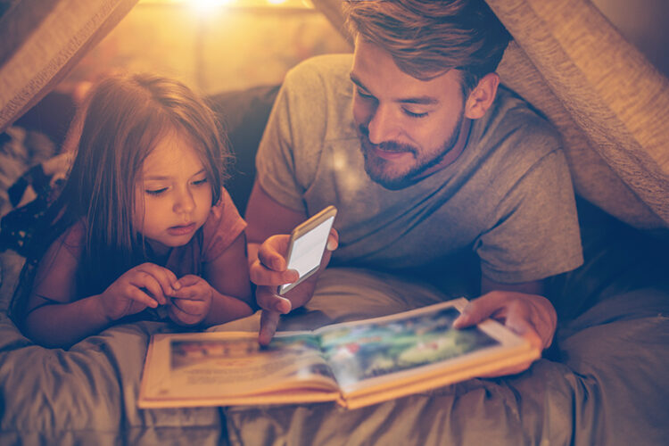 Pappa och dotter läser bok i koja.
